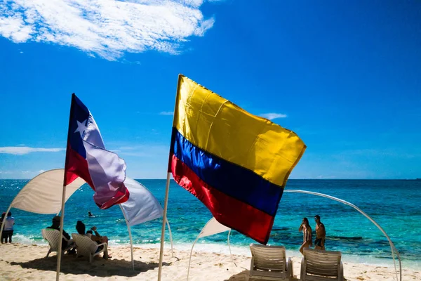 JOHNNY CAY, COLOMBIA - 21 DE OCTUBRE DE 2017: Personas no identificadas caminando por la playa y disfrutando del hermoso día soleado y nadando en el agua en la costa de la isla Johnny Cay con algunas banderas —  Fotos de Stock