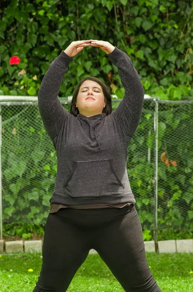 Mujer joven haciendo ejercicio de yoga al aire libre, en un fondo de jardín — Foto de Stock