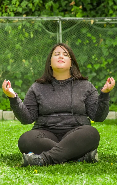 Giovane donna che fa esercizio di yoga all'aperto, loto posa meditazione in uno sfondo giardino — Foto Stock