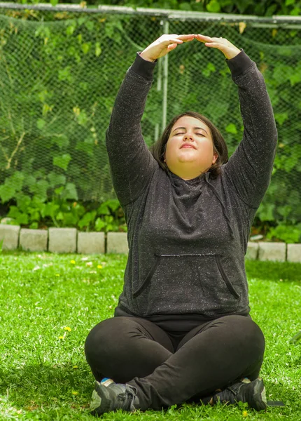 Mujer joven haciendo ejercicio de yoga al aire libre, en un fondo de jardín —  Fotos de Stock