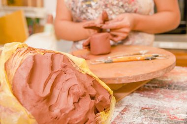 Bir kil kitle heykel Atölyesi, arka plan bulanık ahşap tablo üzerinde çalışan arkasında bir bulanık kadın ustası ile yakın çekim