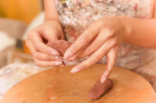 Close up of woman ceramist hands working on sculpture on wooden table in workshop — Stock Photo, Image