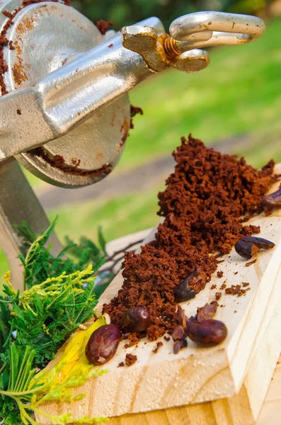Зовнішній вигляд какао-бобів і какао-фрезерування на дерев'яному столі, з ручним млином, на розмитому фоні природи — стокове фото