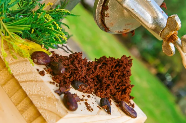 Крупним планом какао-боби і какао-фрезерування на дерев'яному столі, з ручним млином, на розмитому фоні природи — стокове фото