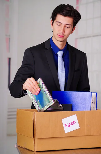 Close up of sad man packing his belongings after being fired from his job in a blurred background — Stock Photo, Image