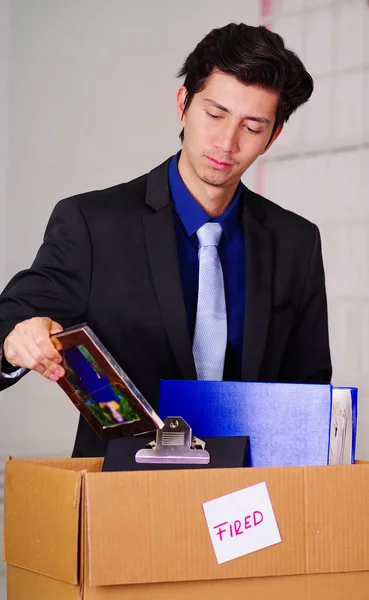 Nahaufnahme eines traurigen Mannes, der seine Habseligkeiten packt, nachdem er vor verschwommenem Hintergrund von seinem Arbeitsplatz gefeuert wurde — Stockfoto