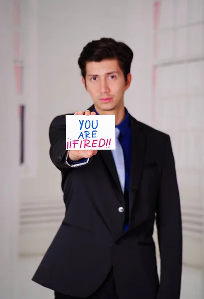 Sad business man holding a paper youre fired text on it, in a blurred background — Stock Photo, Image