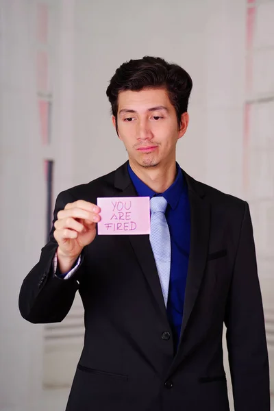 Sad business man holding a paper of youre fired text on it, in a blurred background — Stock Photo, Image