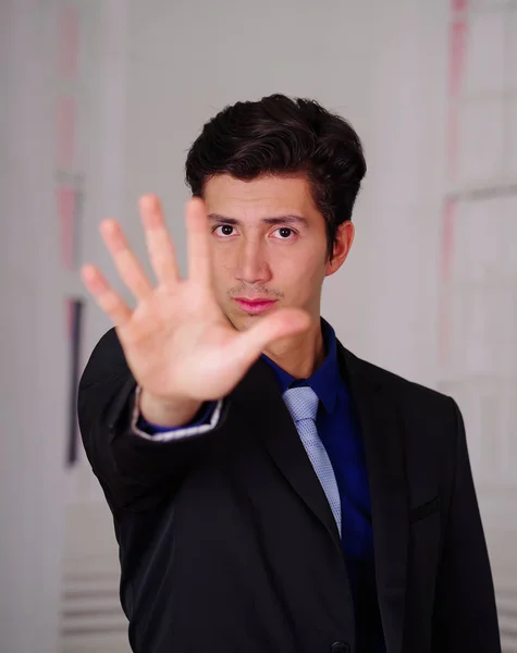 Close up of boss wearing a suit with his open hand pointing in front of him, in a blurred background — Stock Photo, Image