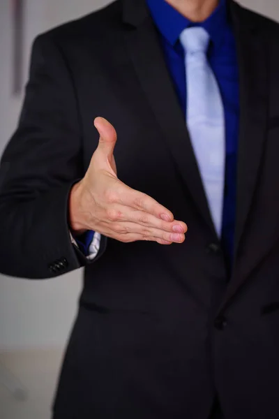 Close up de homem vestindo um terno com a mão aberta na frente dele, em um fundo embaçado — Fotografia de Stock