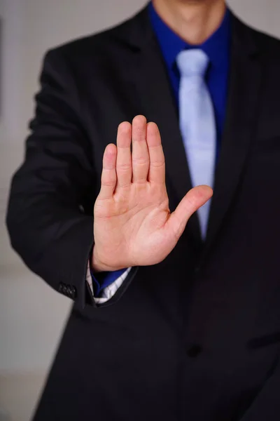 Close up de homem vestindo um terno com a mão aberta apontando na frente dele, em um fundo embaçado — Fotografia de Stock