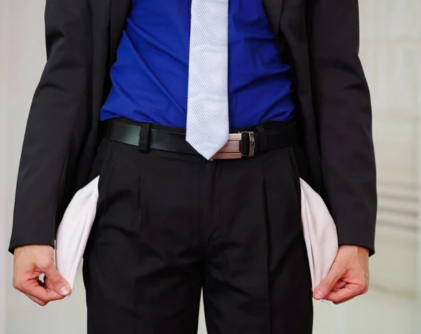 Close up of down part of a man wearing a suit holding his empty pockets consequence of being fired, in a blurred background — Stock Photo, Image