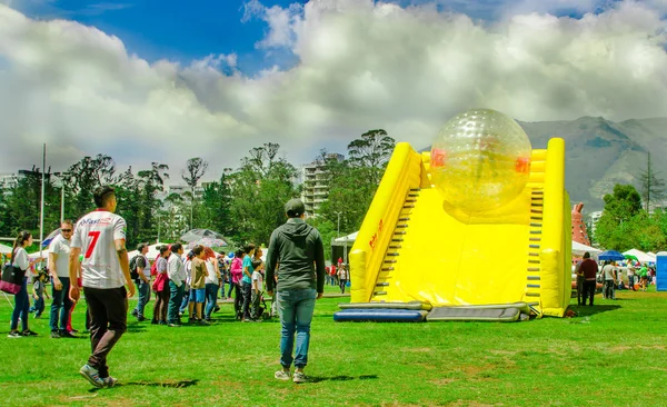 QUITO, ECUADOR - 28 NOVEMBRE 2017: Veduta esterna di giovani non identificati all'interno di una palla gonfiabile gigante trasparente che scivola in uno scivolo di plastica gialla nel Carolina Park durante un festival in — Foto Stock