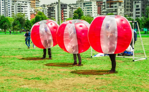 QUITO, ECUADOR - 28 DE NOVIEMBRE DE 2017: Jóvenes no identificados jugando al fútbol mientras están dentro de pelotas rojas inflables gigantes en el Parque Carolina durante un festival en la ciudad de Quito — Foto de Stock