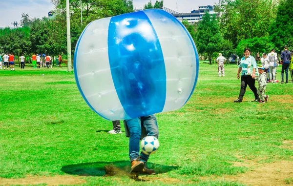 QUITO, ECUADOR - 28 DE NOVIEMBRE DE 2017: Joven jugando al fútbol mientras está dentro de una bola inflable gigante en el Parque Carolina durante un festival — Foto de Stock