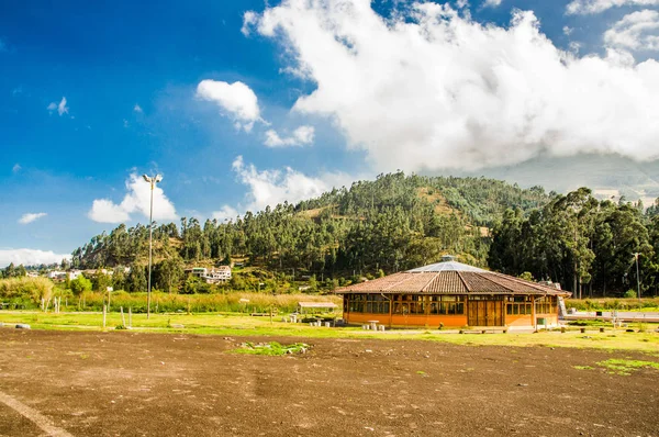 Hermosa vista de una construcción de casa de madera en medio del valle en un hermoso día con cielo azul y algunas nubes, con un bosque detrás — Foto de Stock