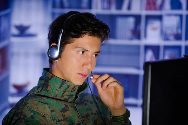Retrato de un joven soldado guapo con uniforme militar, operador militar de drones mirando su computadora y usando sus auriculares para dar un consejo —  Fotos de Stock