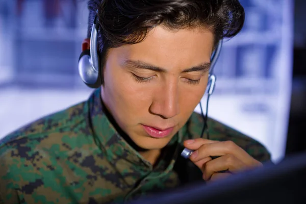 Porträt eines Soldaten in Militäruniform, der an seinem Computer arbeitet und über Kopfhörer einen Rat gibt — Stockfoto