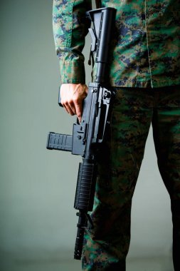 Bir tüfek, askerin gri bir arka planda bir askeri üniforma giydiği bildirildi, yakın çekim
