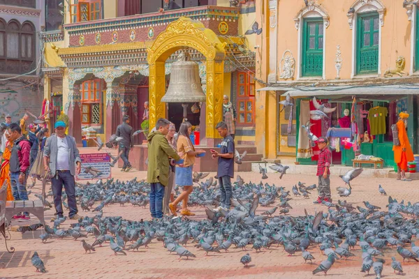 KATHMANDU, NEPAL OCTUBRE 15, 2017: Personas no identificadas caminando en la plaza que rodea a cientos de palomas frente a una enorme campana bajo una estructura de oro apedreado en Katmandú Boudhanath Stupa en — Foto de Stock