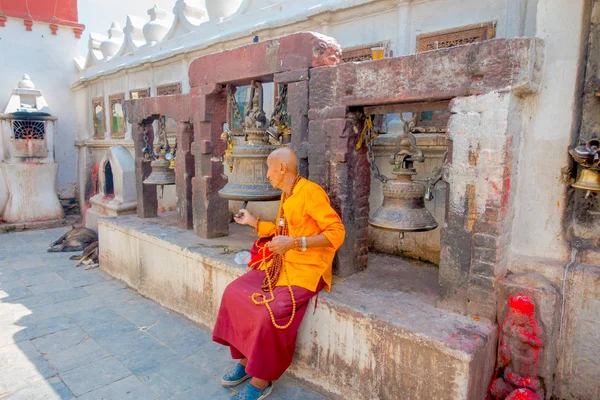 Kathmandu, Nepal 15. Oktober 2017: Nahaufnahme eines unbekannten Mannes, der im Freien sitzt und in einer Hand Gebetsperlen hält und mit der anderen Hand eine riesige Glocke in der Nähe des Monuments boudhanath berührt — Stockfoto