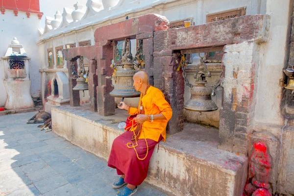 KATHMANDU, NEPAL 15 OCTOBRE 2017 : Gros plan d'un homme non identifié assis à l'extérieur et tenant dans une main des perles de prière et touchant une énorme cloche avec son autre main près du monument Boudhanath — Photo