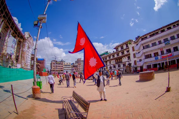 カトマンズ, ネパール 2017 年 10 月 15 日: 不明の人が歩く街とカトマンズのダルバール広場で彼の手のフラグを保持しているネパール人、魚、ネパールの首都の目の効果 — ストック写真