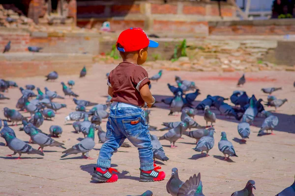 KATHMANDU, NEPAL - 26 avril 2012 : Petit enfant noir non identifié marchant dans la rue avec un troupeau de pigeons, sur la place Durbar près de vieux temples hindous à Katmandou, au Népal — Photo