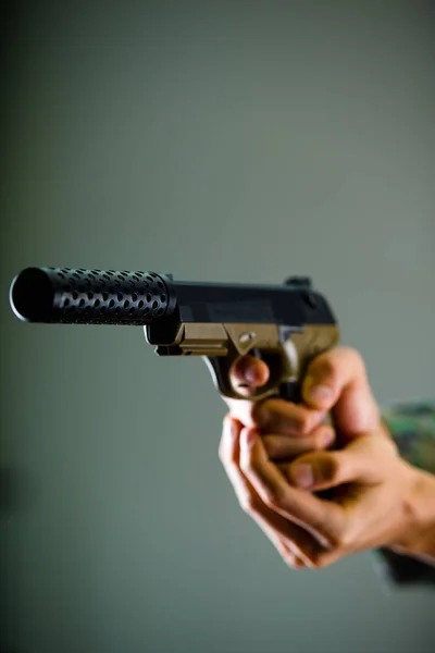 Внутренний вид солдата, держащего в руках пистолет на сером фоне — стоковое фото