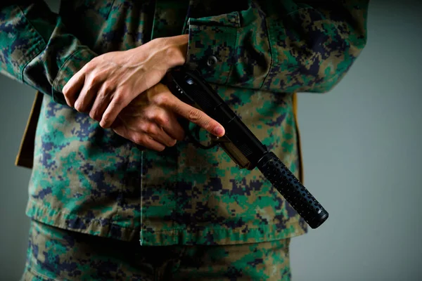 Zbliżenie na ręce Żołnierz trzyma broń w szarym tle — Zdjęcie stockowe