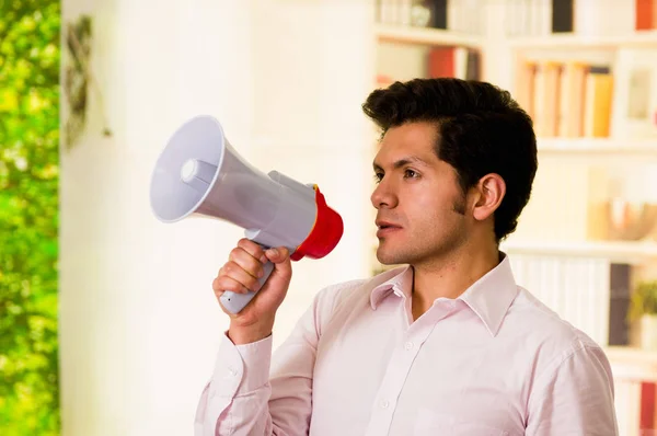 Acercamiento de un hombre guapo y serio sosteniendo un megáfono en su mano en un fondo borroso — Foto de Stock