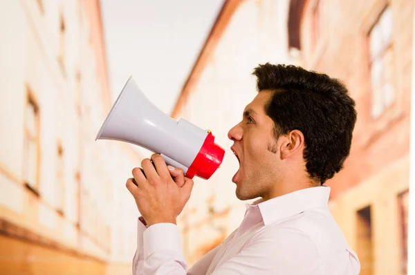 Primer plano de un hombre guapo gritando con un megáfono en un fondo borroso — Foto de Stock