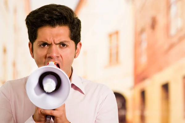 Nahaufnahme eines gutaussehenden Mannes, der mit einem Megafon vor verschwommenem Hintergrund schreit — Stockfoto