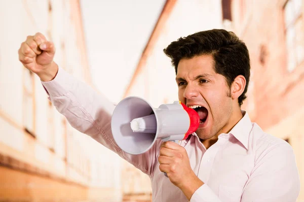 Nær en kjekk mann som skriker med en megafon i utydelig bakgrunn – stockfoto