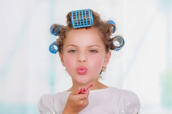 Petite fille peignant les lèvres tout en portant des rouleaux de cheveux et peignoir — Photo