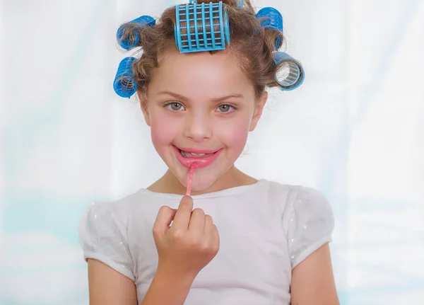 Portret van meisje schilderij lippen terwijl het dragen van de rollers en badjas — Stockfoto