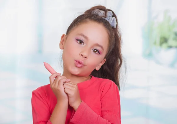 Close up van mooie meisje bedrijf in haar handen een lippenstift in een onscherpe achtergrond — Stockfoto