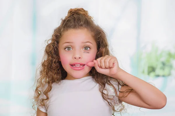 Close up of little surprised beautiful girl using wrong a lipstick in a blurred background — Stock Photo, Image