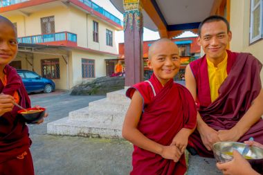 Pokhara, Nepal - 06 Ekim 2017: Metalik bir kase çorba ile elinde tutan ve açık havada, Tashi mülteci yerleşim, onların arkadaşları ile konuşurken tanımlanamayan Budist keşiş genç