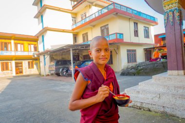 Pokhara, Nepal - 06 Ekim 2017: Budist keşiş gencin elinde metalik bir kase çorba, Tashi mülteci yerleşim Pokhara, Nepal, açık havada tutan kapat