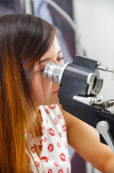 Oidentifierad kvinna checkar vision av modern utrustning, ögon examen i optiska, i en suddig bakgrund — Stockfoto