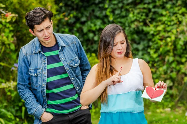 Close up of young woman with a disgusting face holding in her hands a letter, with a worried boyfriend looking his girlfriend, friend zone concept — Stock Photo, Image