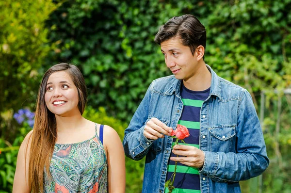 Gros plan d'un beau couple amoureux dans un parc, femme souriante tandis que l'homme joue avec une fleur et regarde son béguin — Photo