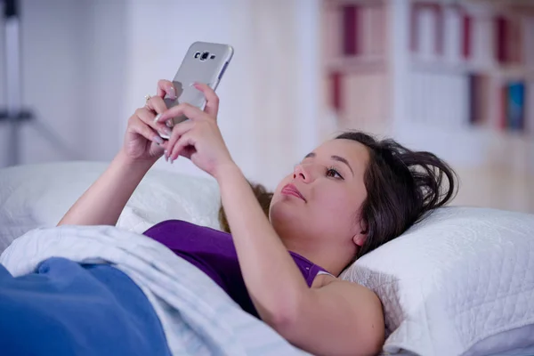 Close up de uma jovem mulher bonita que sofre de insônia e usando seu celular na cama — Fotografia de Stock