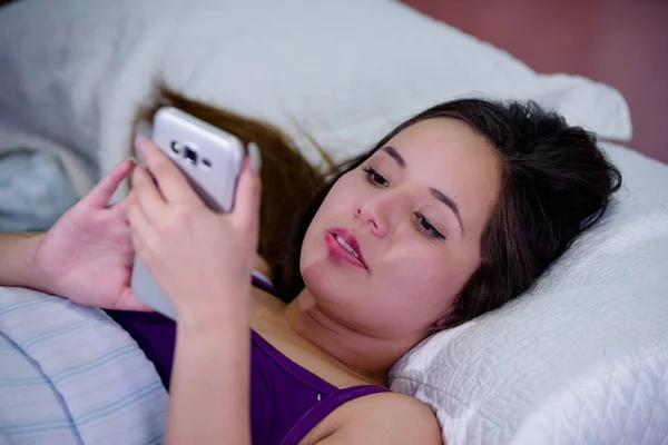 Retrato de una joven que sufre de insomnio y usa su celular en la cama — Foto de Stock