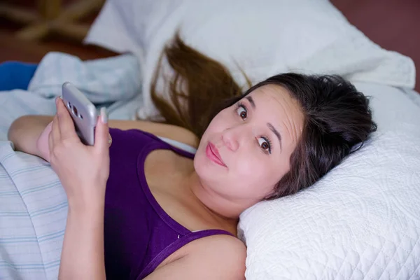 Retrato de una joven que sufre de insomnio y usa su celular en la cama — Foto de Stock