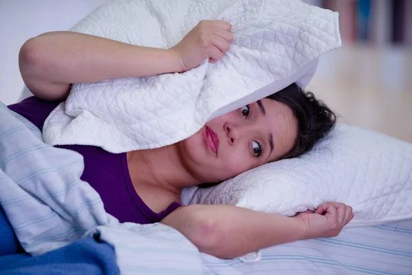 Acercamiento de la joven hermosa mujer que sufre de insomnio con una almohada sobre su cabeza —  Fotos de Stock
