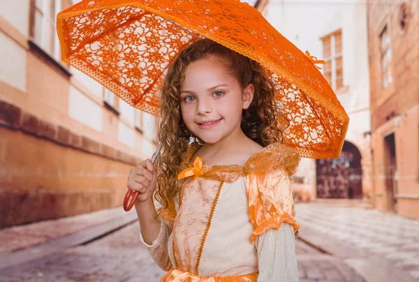 美しい植民地時代の衣装を着ていると、背景をぼかして、オレンジ色の傘を保持している美しい少女のクローズ アップ — ストック写真
