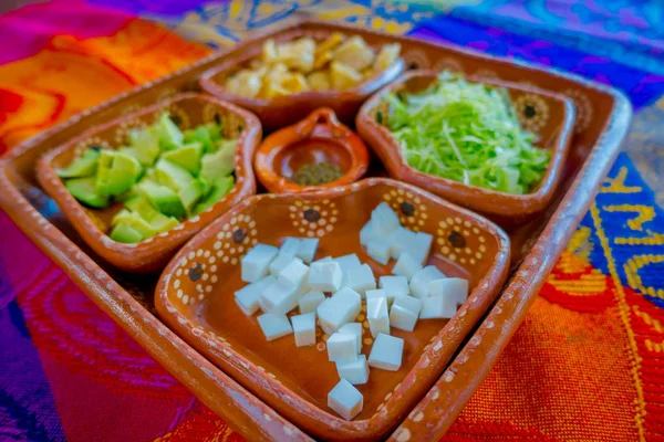 Herkullinen perinteinen meksikolainen ruoka Cozumelin alueelta, valkoinen kastike, salaatti ja avokado savilevyjen sisällä savitarjottimella, joka tarjoillaan pöydän yli kastikkeen keskellä levyjä. — kuvapankkivalokuva
