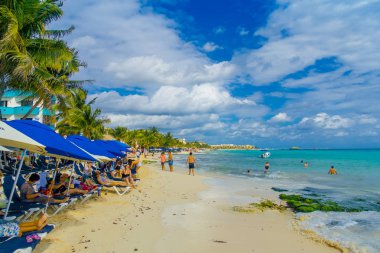Bir Playa del Carmen, Meksika - 10 Ocak 2018: bir şemsiye altında oturan ve gün batımında sahilde Playa del Carmen zevk tanımlanamayan kişi